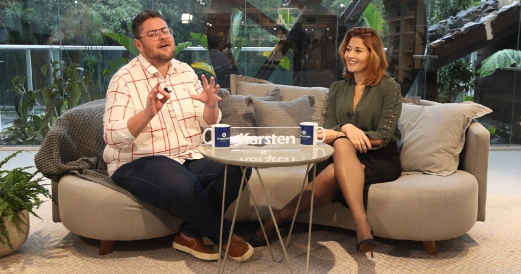 joanna tomio e gustavo siqueira sentados em sofá durante entrevista